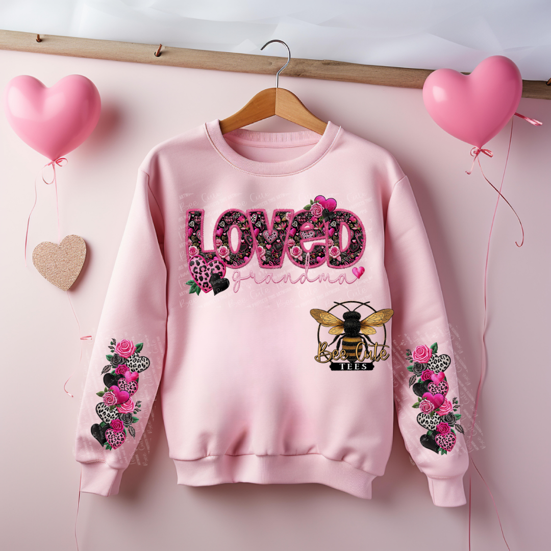 Pink sweatshirt with floral designs and 'LOVED' text on a pink background with heart balloons.