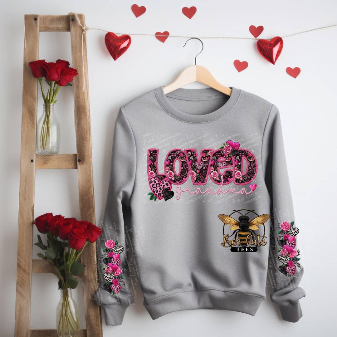 Gray sweatshirt with floral designs and text, hanging on a wooden hanger against a white wall with heart decorations.