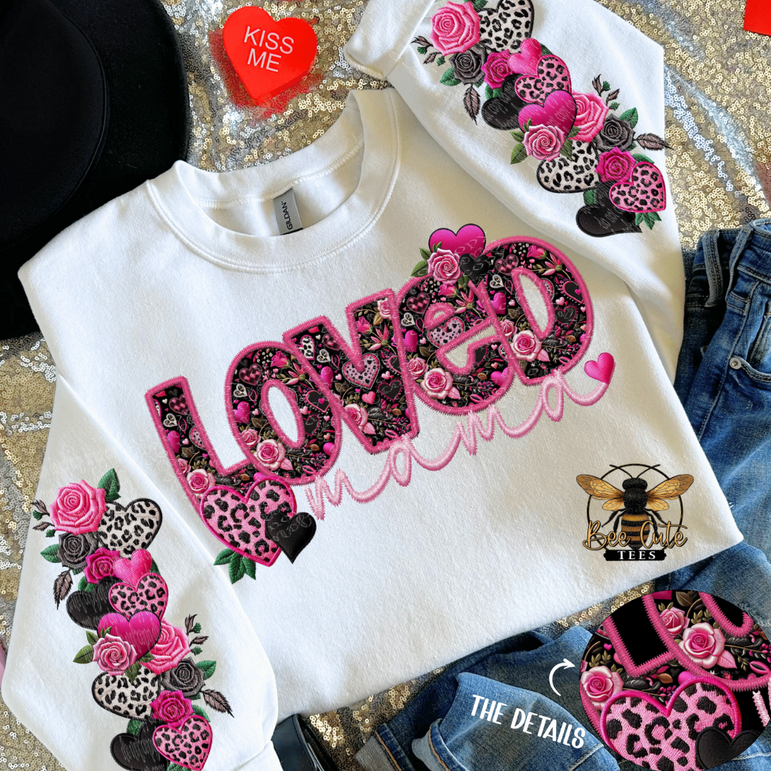 White sweatshirt with floral and bee designs, and 'LOVED' text on a patterned surface.