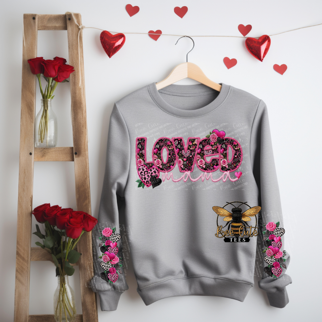 Gray sweatshirt with floral designs and text, hanging on a wooden hanger against a white wall with heart decorations.