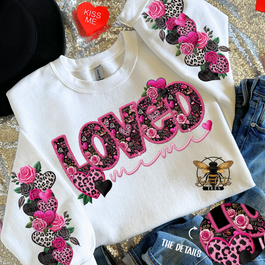 White sweatshirt with decorative text and graphics on a patterned surface