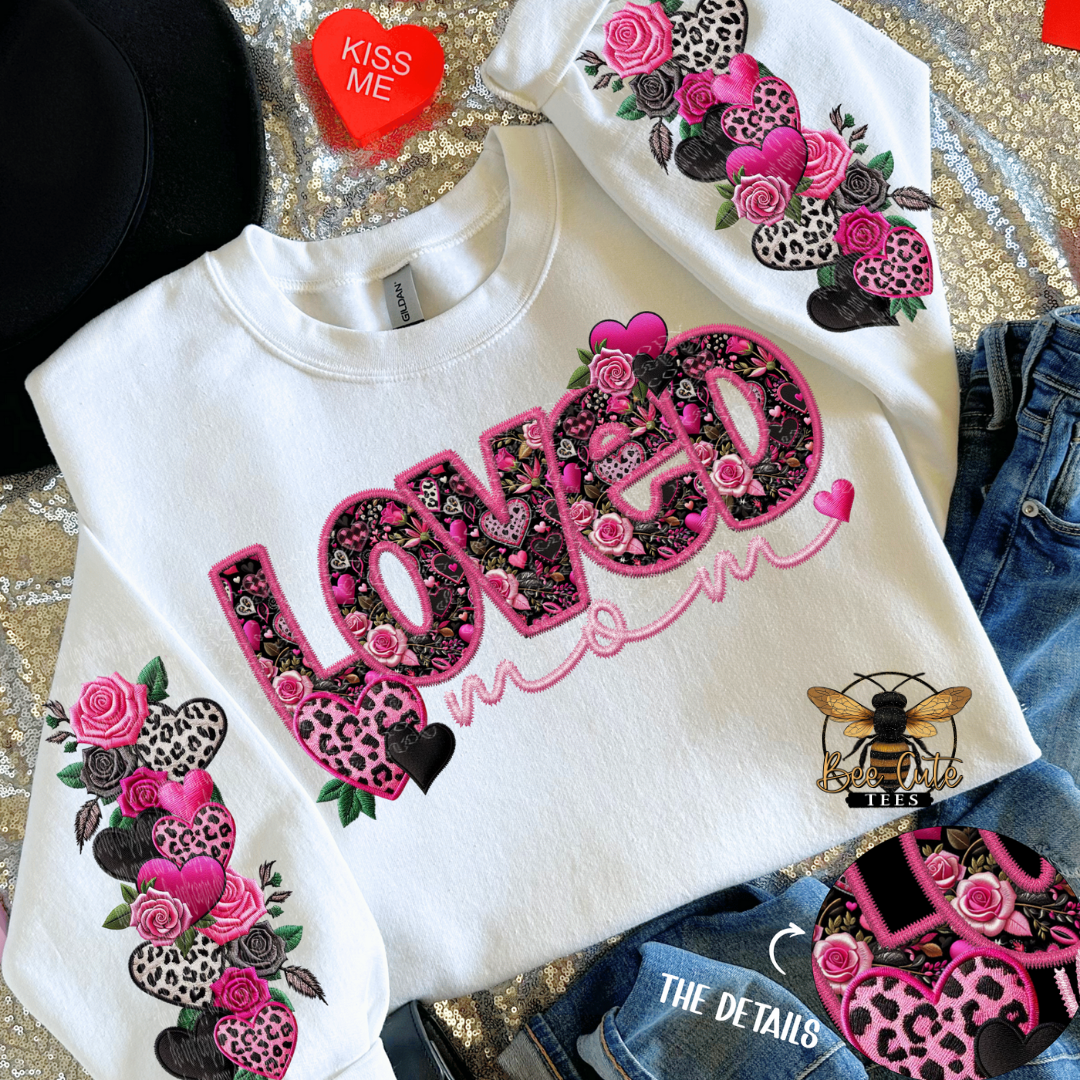 White sweatshirt with floral and heart designs on a textured surface