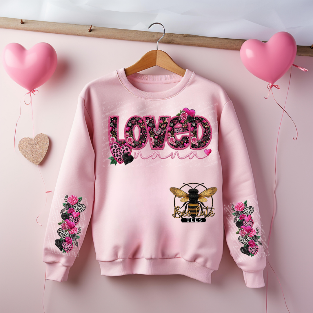 Pink sweatshirt with floral designs and text on a pink background with balloons.