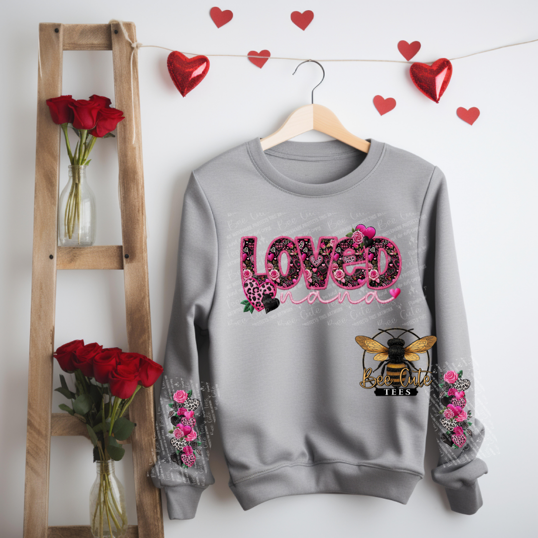 Gray sweatshirt with floral text and bee design hanging on a wooden ladder with red roses and heart decorations.