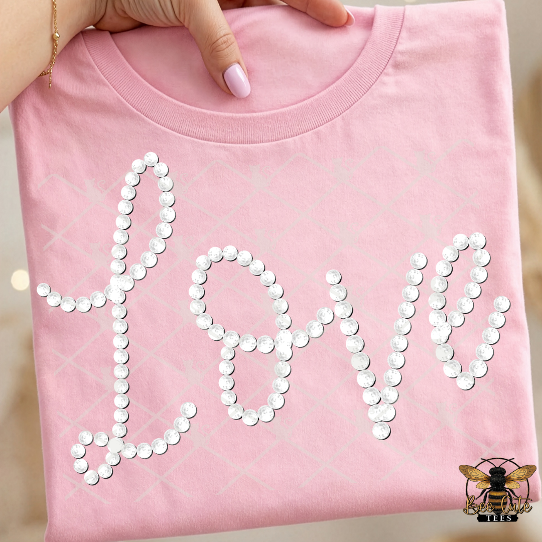Pink sweatshirt with 'LOVE' made of faux white pearls held by a hand.