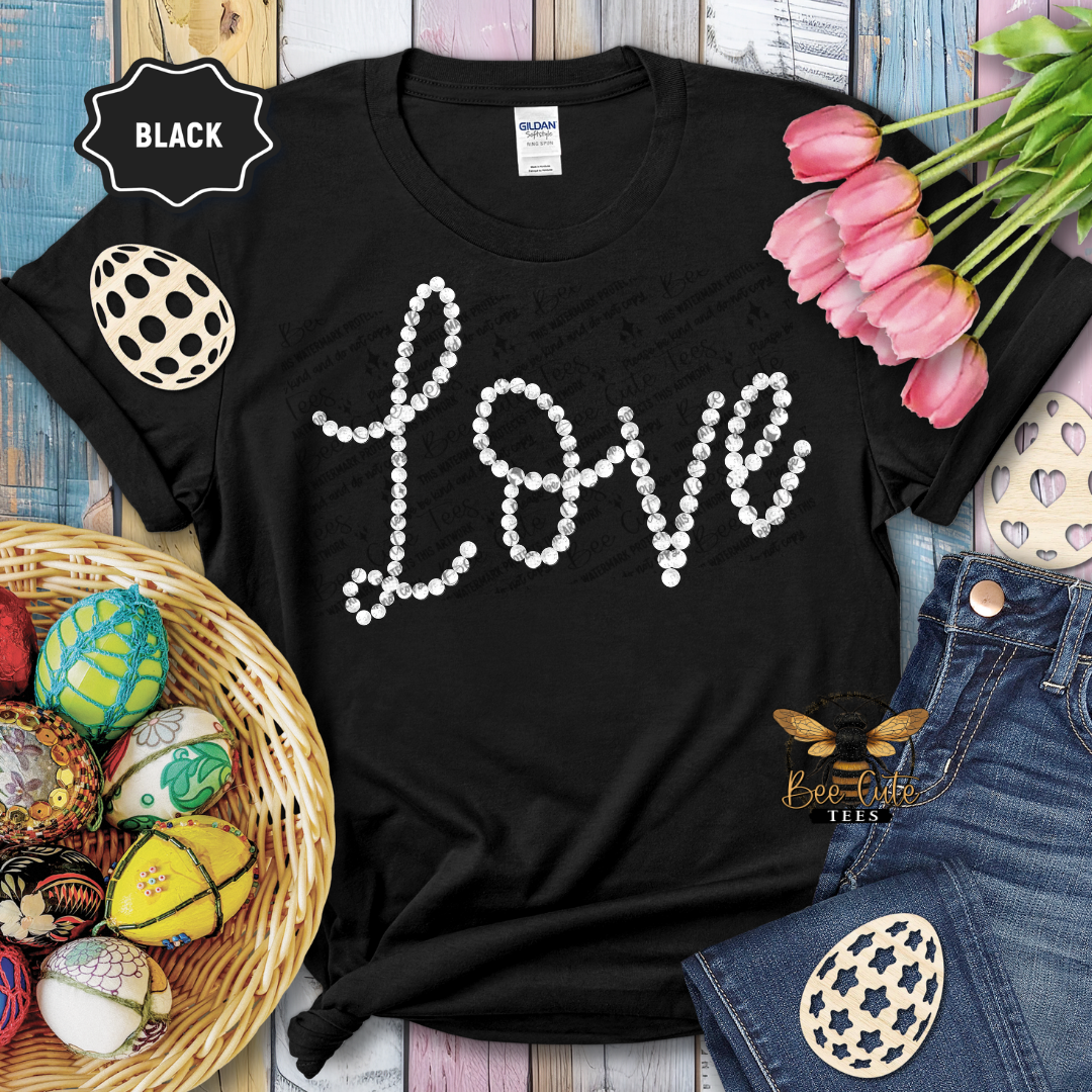 Black t-shirt with 'LOVE' in pearls, surrounded by Easter decorations on a wooden surface.