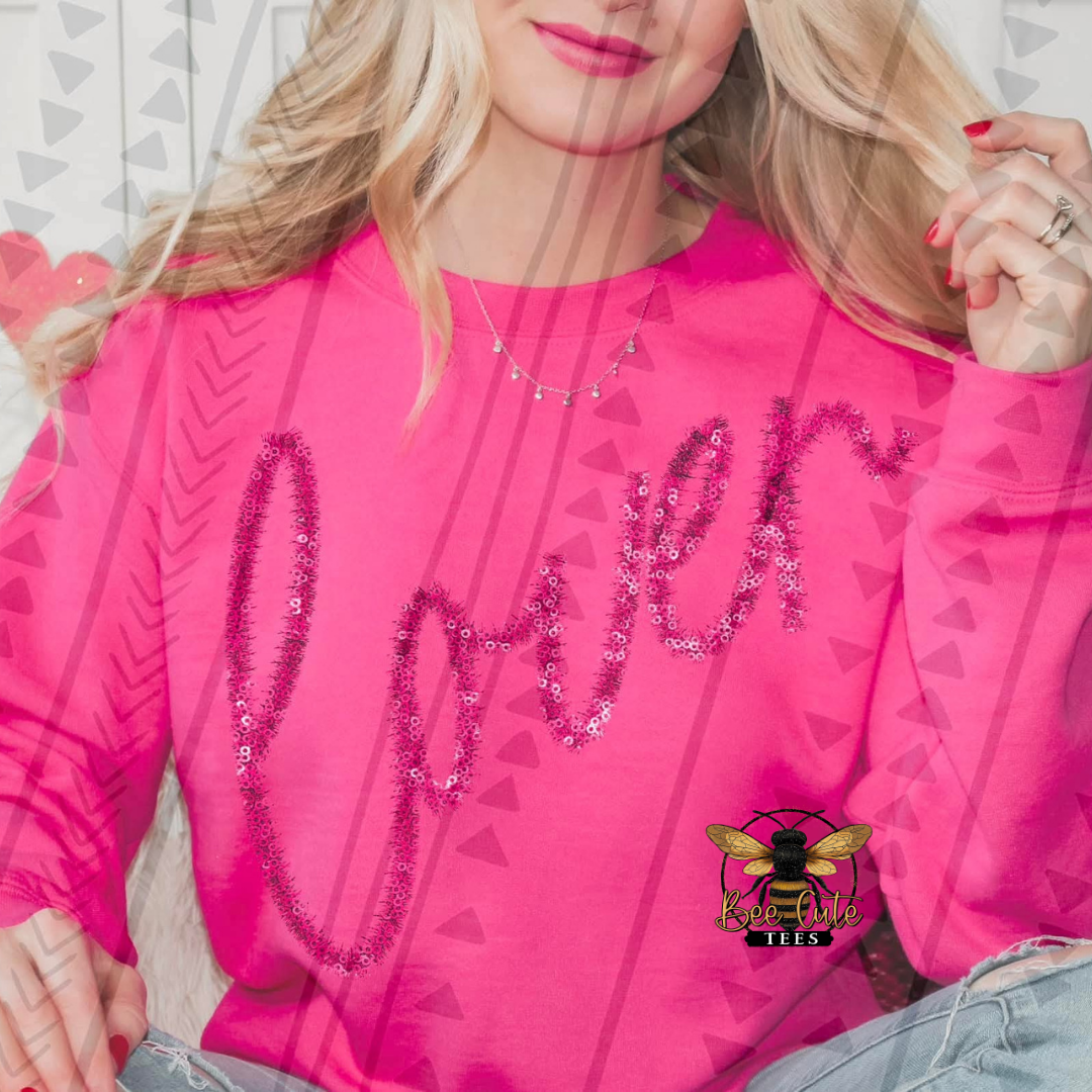 Person wearing a pink sweatshirt with 'lover' text, sitting on a white surface.