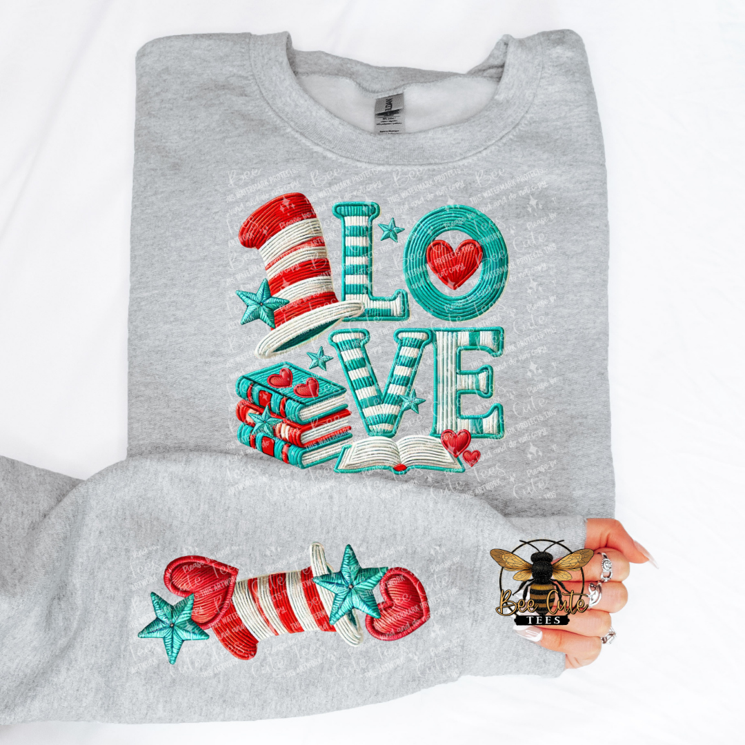Folded gray sweatshirt with colorful 'LOVE' design featuring a hat, books, and hearts.