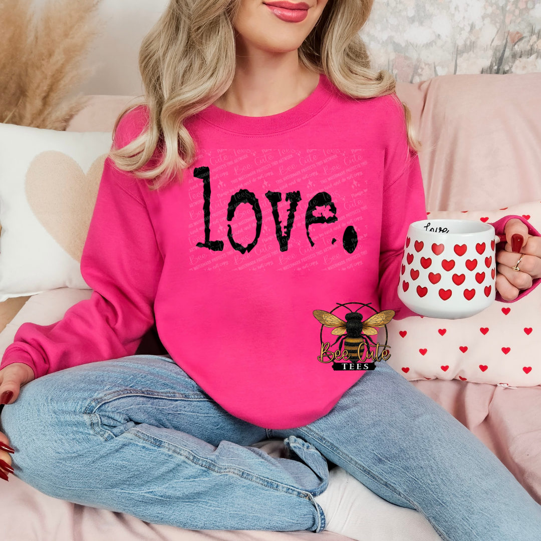 Person wearing a pink sweatshirt with 'love' printed on it, holding a mug with heart patterns.