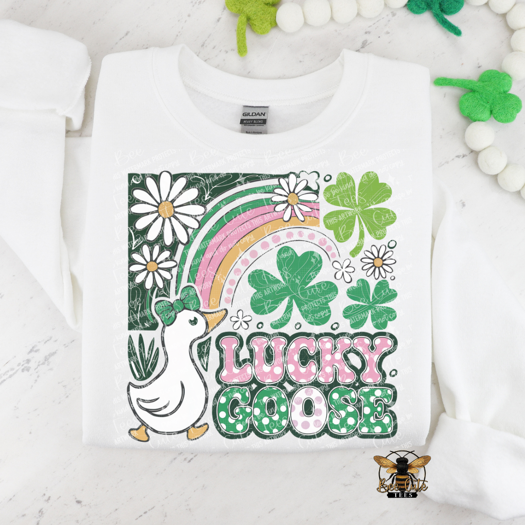 White sweatshirt with 'Lucky Goose' design featuring a goose, rainbow, and shamrocks on a white background.