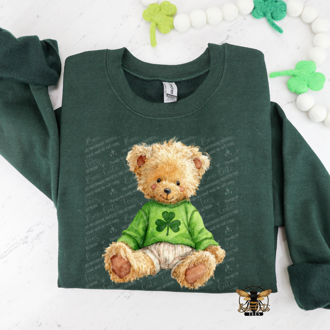 Green sweatshirt with a teddy bear design featuring a four-leaf clover on a white background.