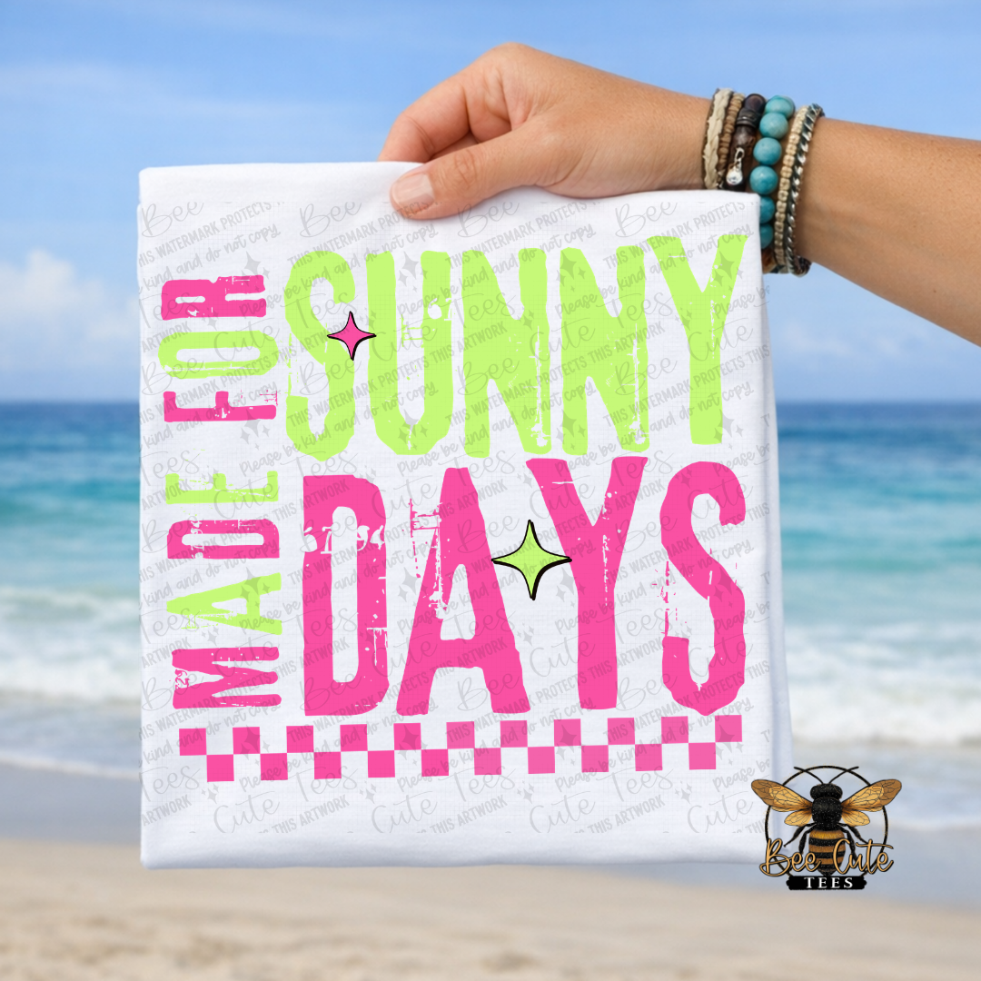 Hand holding a t-shirt with 'Made for Sunny Days' text against a beach background