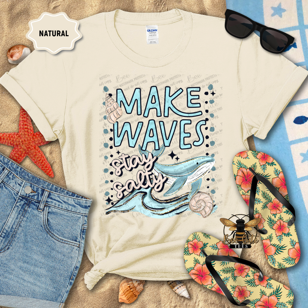 Beige t-shirt with 'Make Waves, Stay Salty' design on a beach-themed background with sunglasses, flip-flops, and starfish.