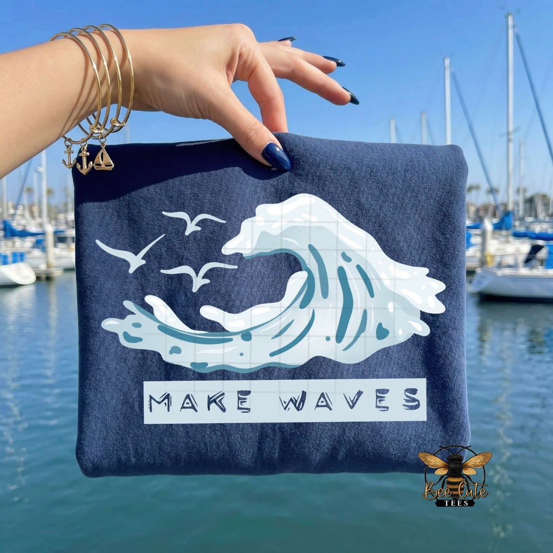 Navy t-shirt with wave design and 'MAKE WAVES' text held by a hand over a marina.