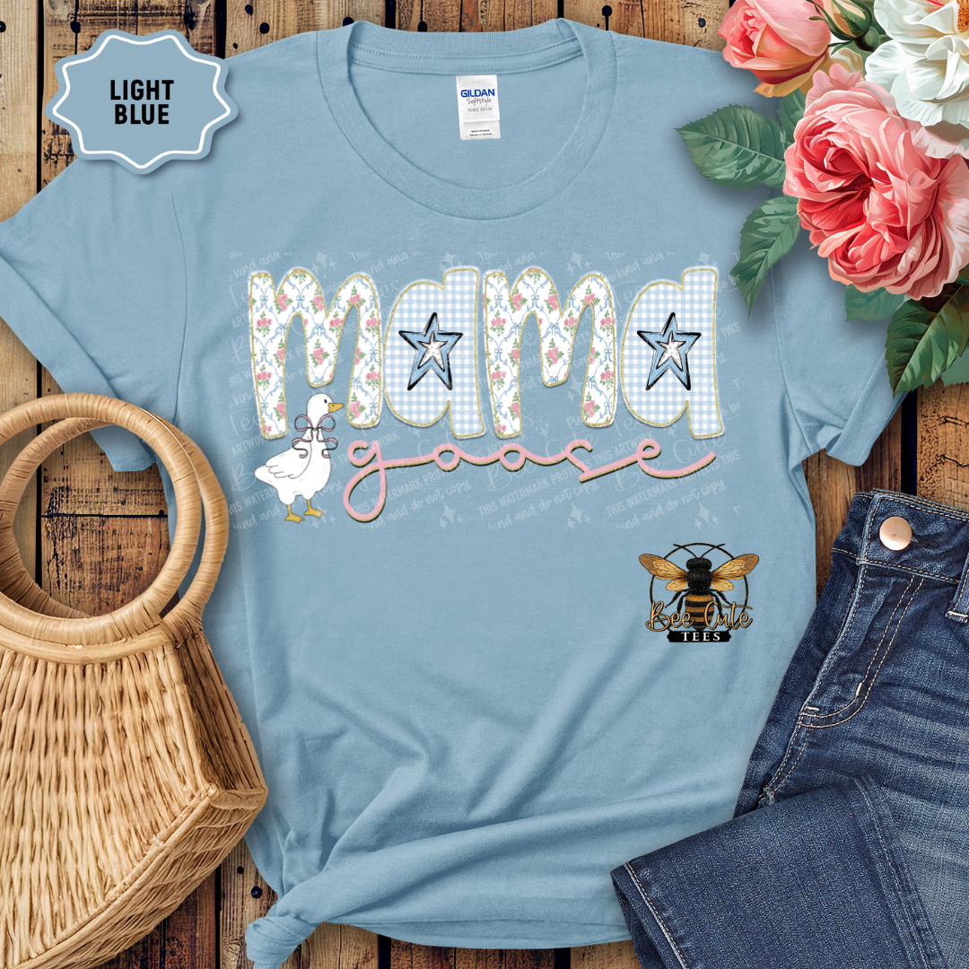 Light blue t-shirt with 'Mama' design on a wooden surface with flowers and jeans.