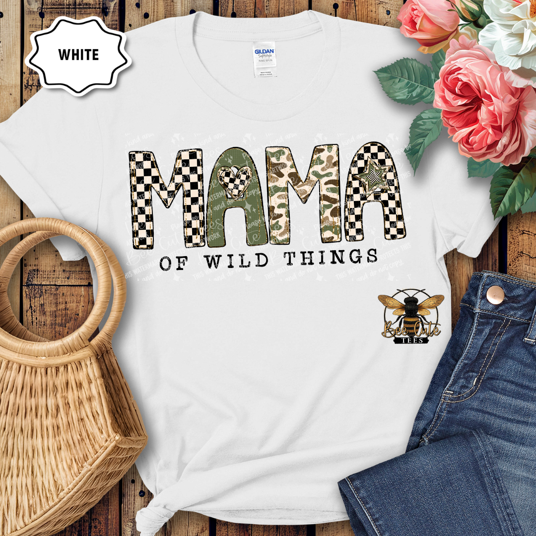 White t-shirt with 'Mama of Wild Things' design on a wooden surface with flowers and jeans.