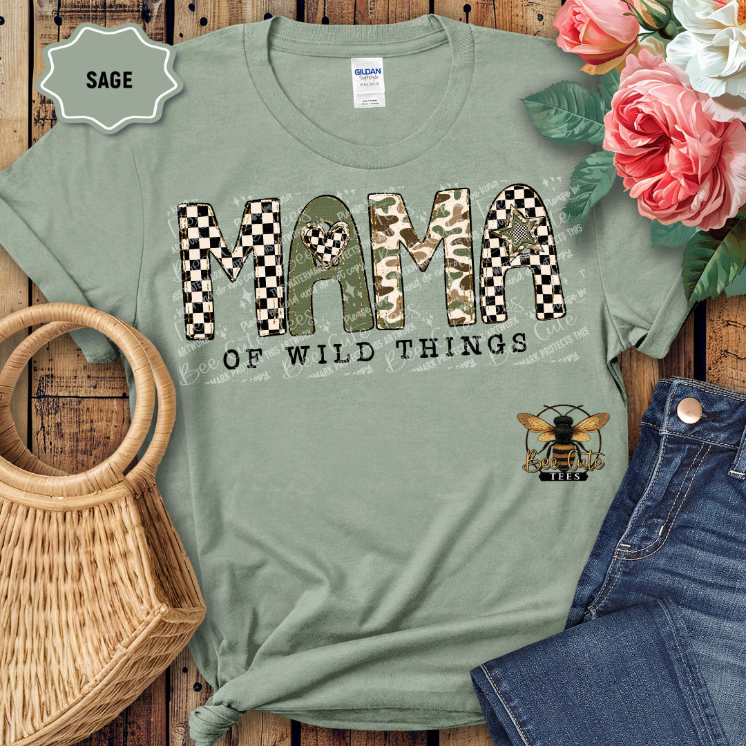 Sage green t-shirt with 'Mama of Wild Things' design on a wooden surface with flowers and jeans.