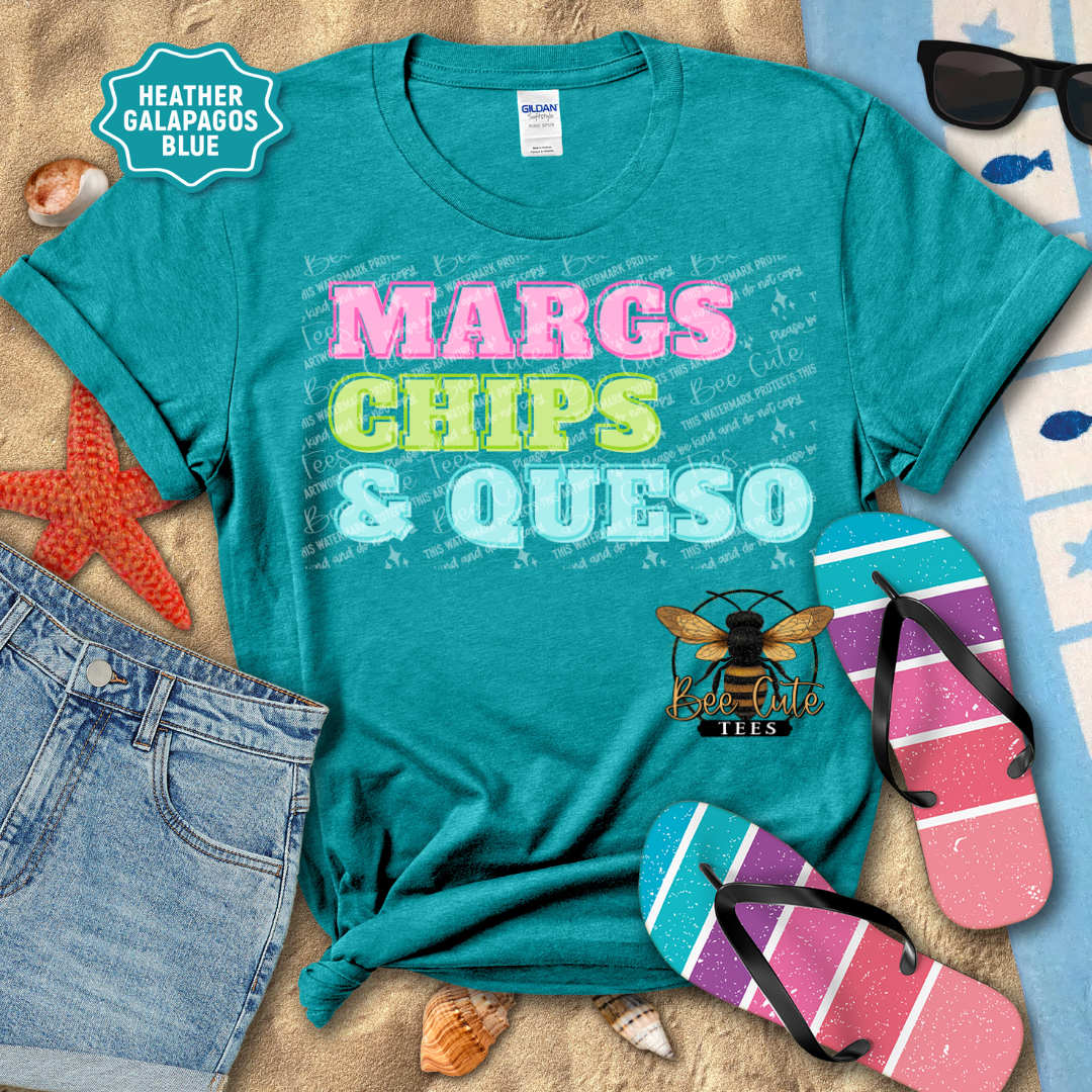 Teal t-shirt with 'MARGS CHIPS & QUESO' text, sunglasses, flip-flops, and beach items on a wooden surface.