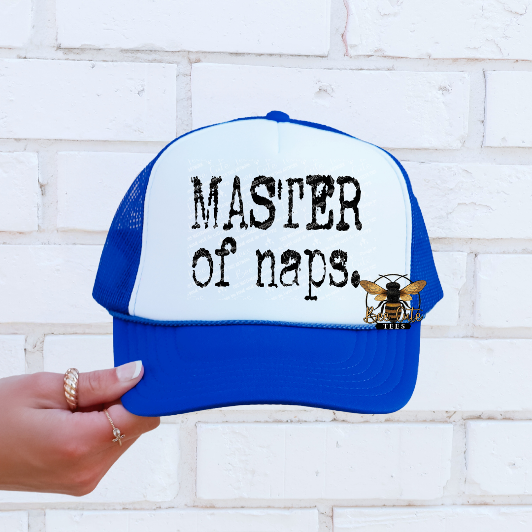 Blue and white cap with 'Master of naps' text held against a white brick wall.