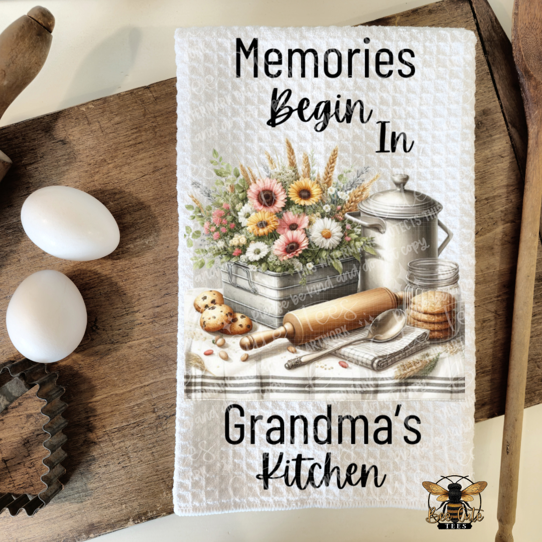 Kitchen towel with floral design and text 'Memories Begin In Grandma's Kitchen' on a wooden surface.