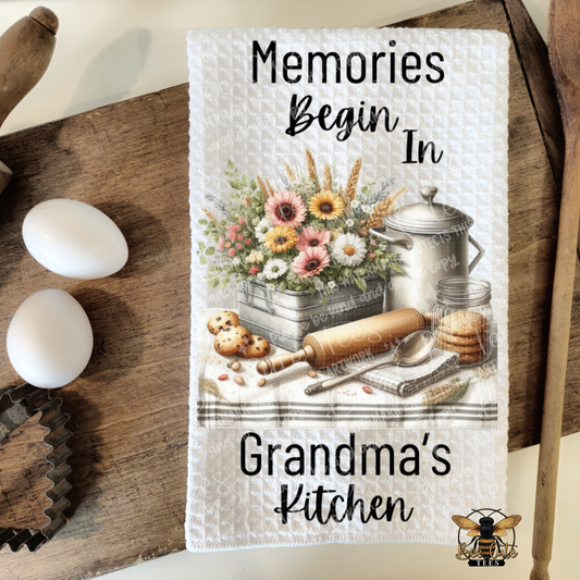Kitchen towel with floral design and text 'Memories Begin In Grandma's Kitchen' on a wooden surface.