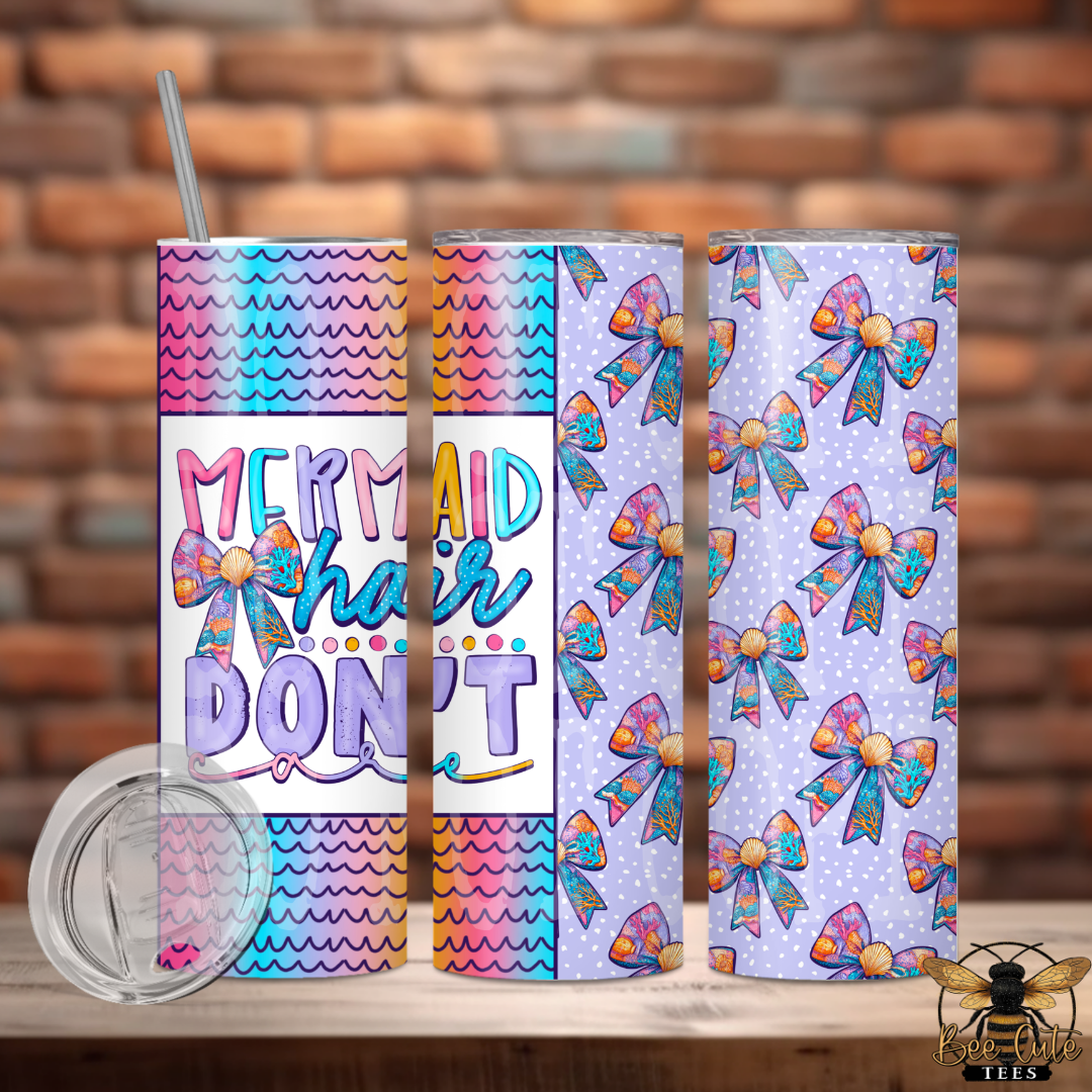 Set of colorful tumblers with bow designs and 'Mermaid hair don't' text against a brick wall background.