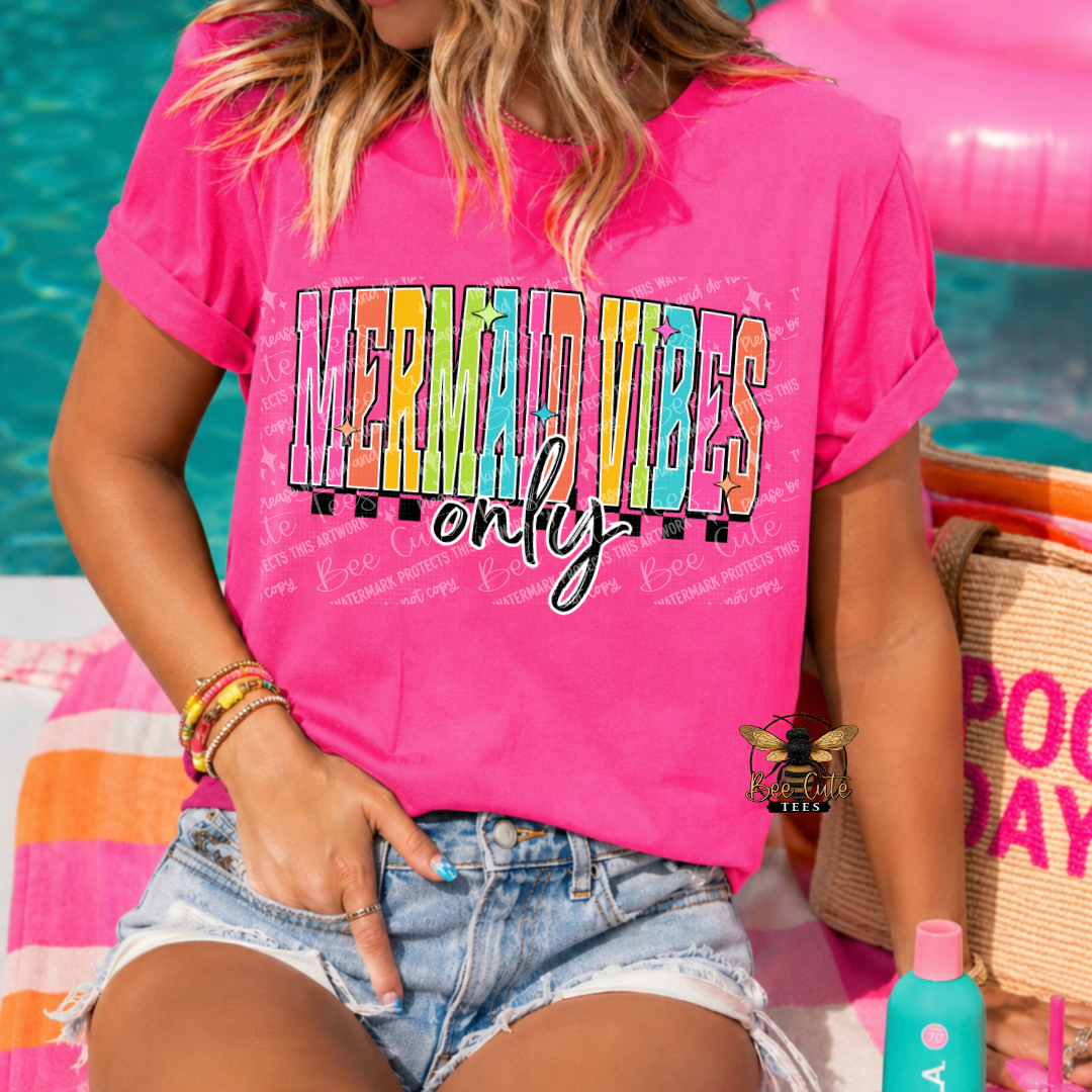 Person wearing a pink t-shirt with 'Mermaid Vibes Only' text, sitting by a pool.