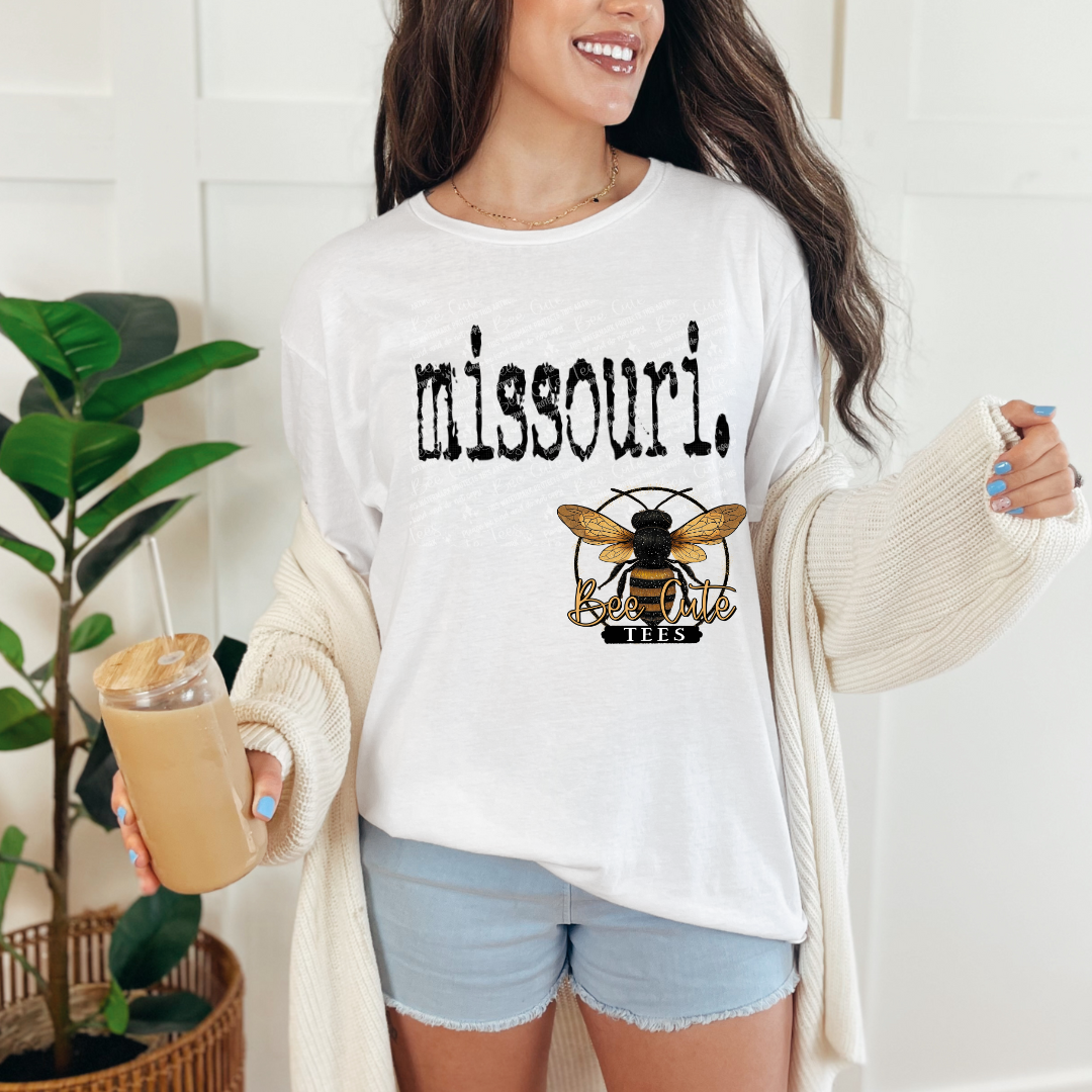 Woman wearing a white sweatshirt with 'missouri', holding a drink.