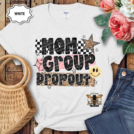 White t-shirt with 'Mom Group Dropout' design on a wooden surface with flowers and jeans.