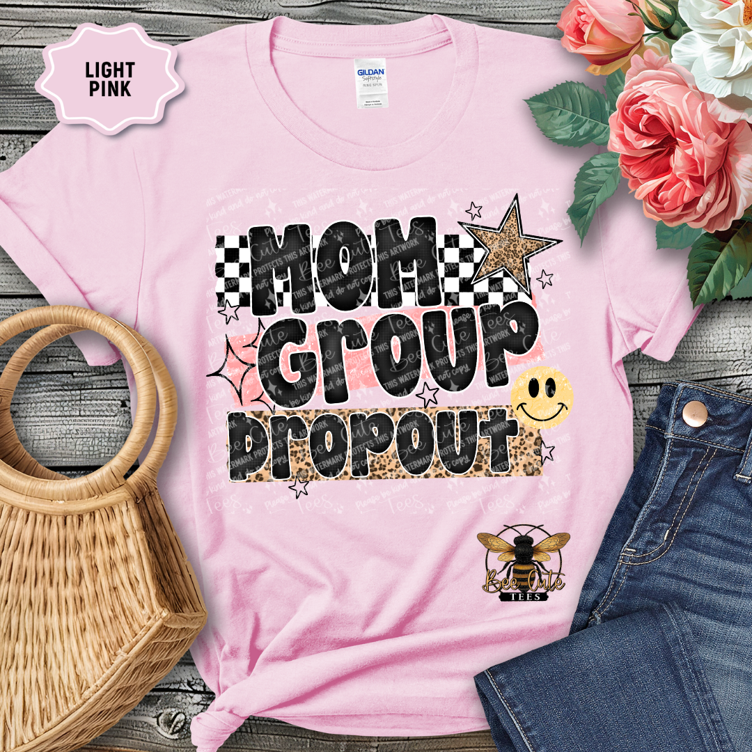 Light pink t-shirt with 'Mom Group Dropout' design on a wooden surface with flowers and denim jeans.