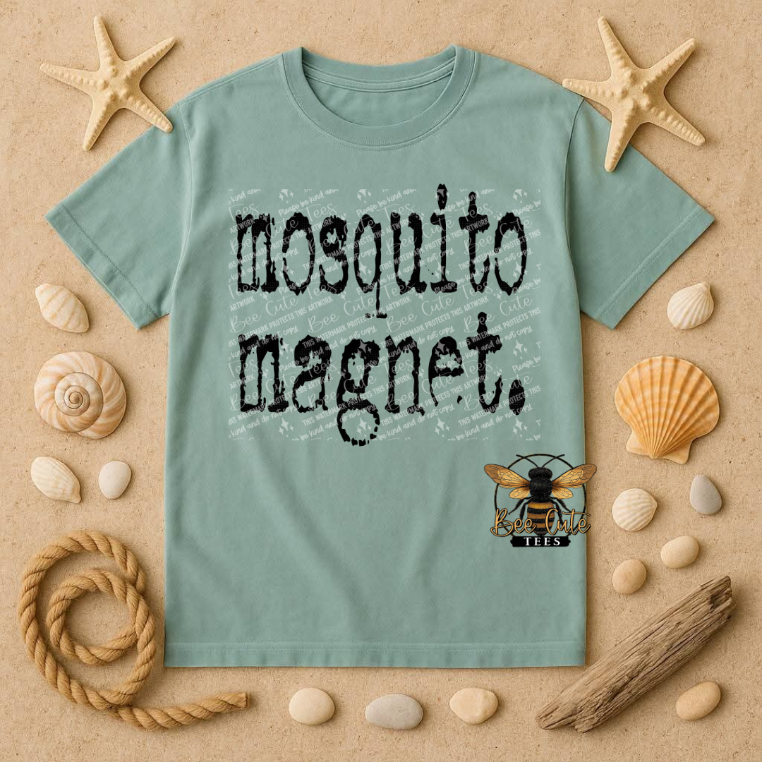 Teal t-shirt with 'mosquito magnet' design on a sandy background with starfish, shells, and rope.