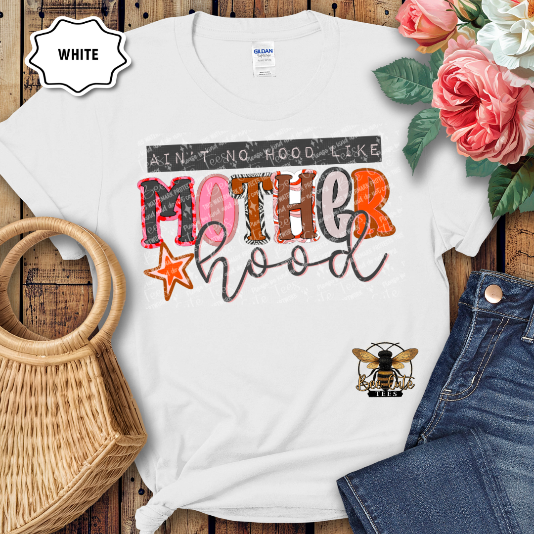 White t-shirt with colorful graphic design on a wooden surface with flowers and jeans.