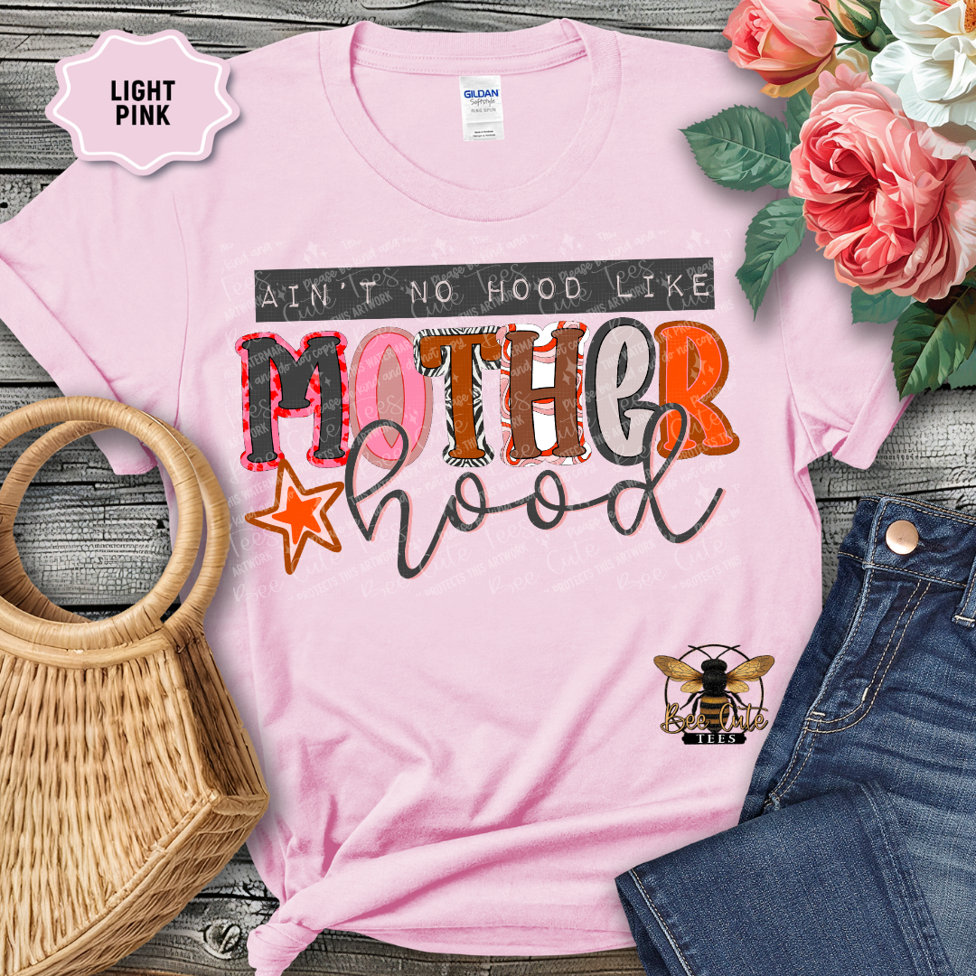 Light pink t-shirt with colorful text and graphics on a wooden surface with flowers and denim jeans.