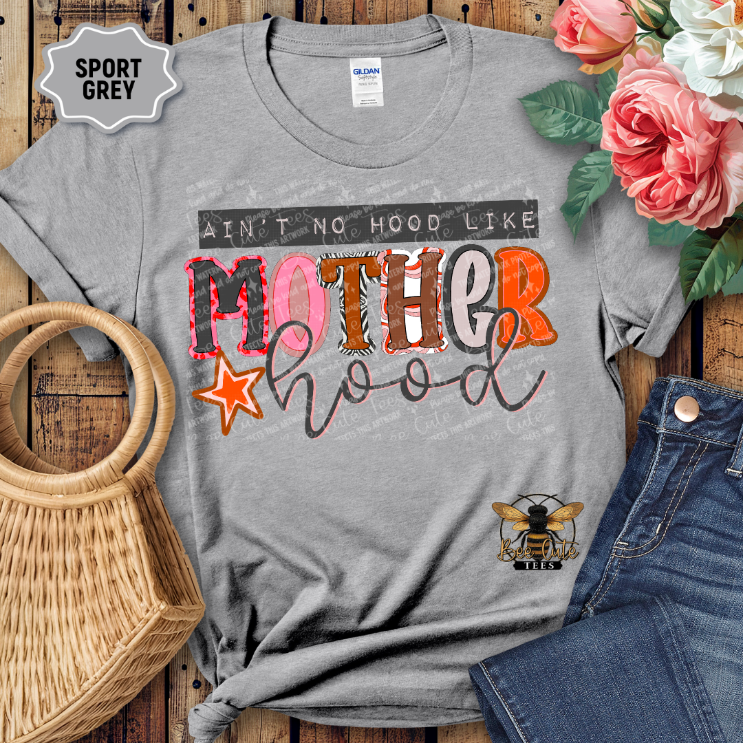 Gray t-shirt with colorful graphic text on a wooden surface with flowers and jeans.