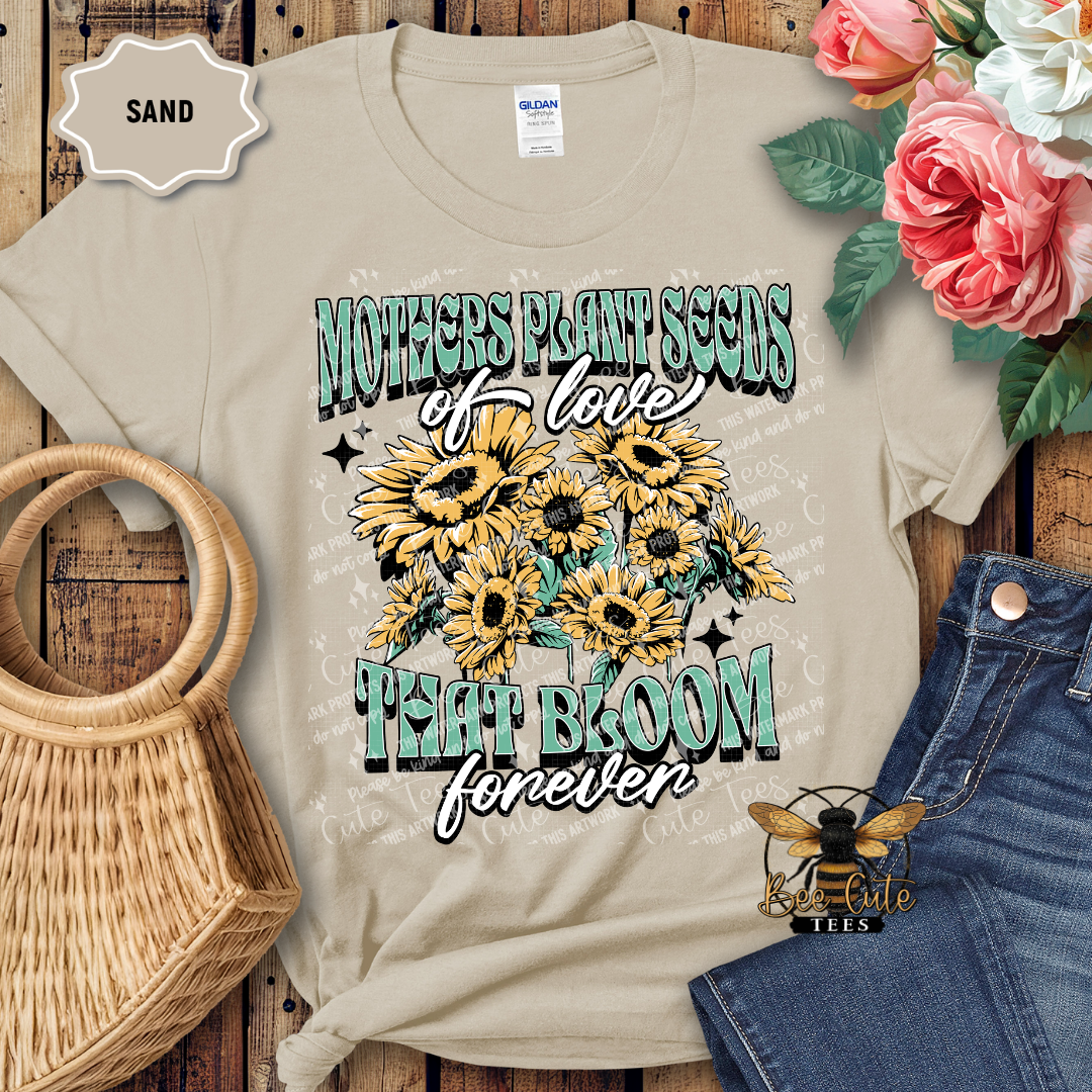 Beige t-shirt with sunflower design and text on a wooden surface with flowers and denim jeans.