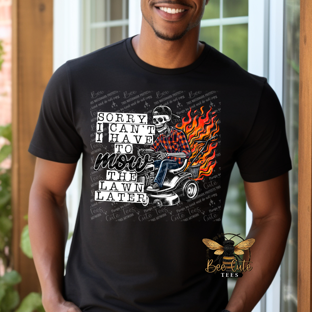 Man wearing a black graphic tee featuring a skeleton riding a lawn mower with flames behind it and the humorous phrase “Sorry, I Can’t, I Have to Mow the Lawn Later.”
