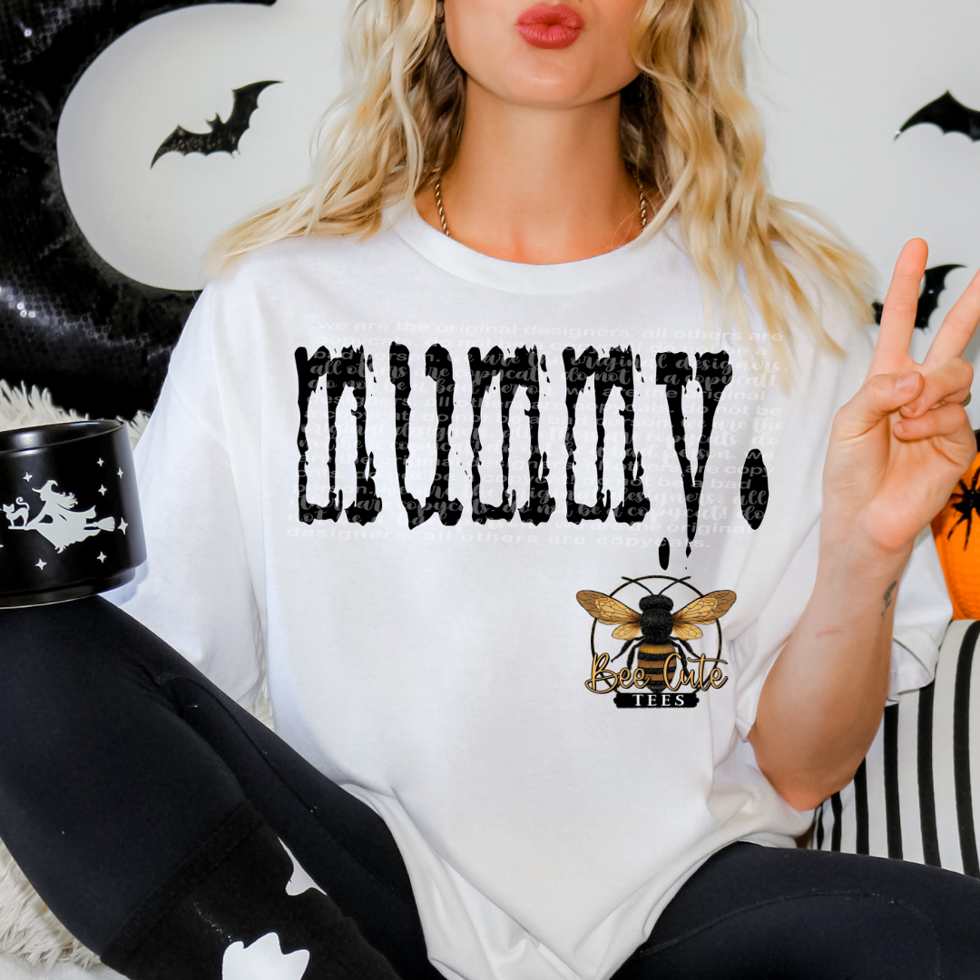 Person wearing a white shirt with 'Mummy' text and bee logo, sitting against a Halloween-themed background.