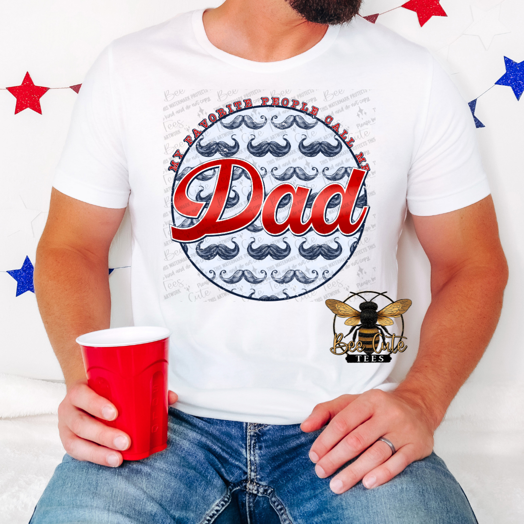 White graphic tee worn by a man holding a red cup, featuring a patriotic-style design with mustaches and the phrase “My favorite people call me Dad” in red and blue lettering.
