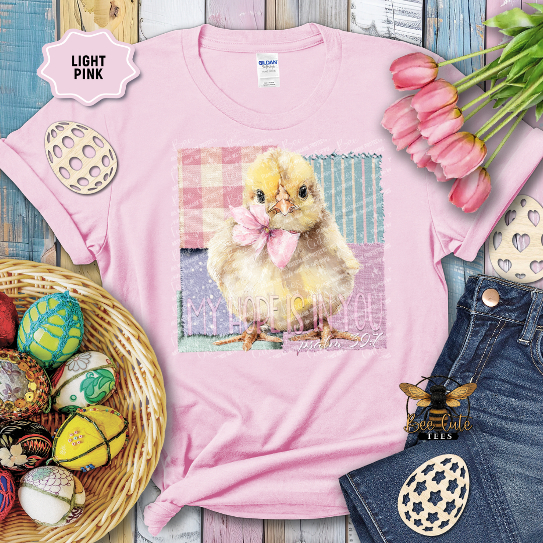 Pink t-shirt with chick graphic and Easter decorations on a wooden surface