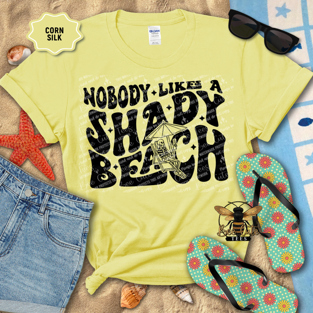 Yellow t-shirt with 'Nobody Likes a Shady Beach' text, sunglasses, and flip-flops on a beach-themed background.
