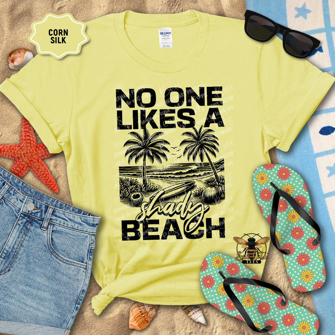 Yellow t-shirt with beach graphic and text, sunglasses, flip-flops, and denim shorts on a sandy background.