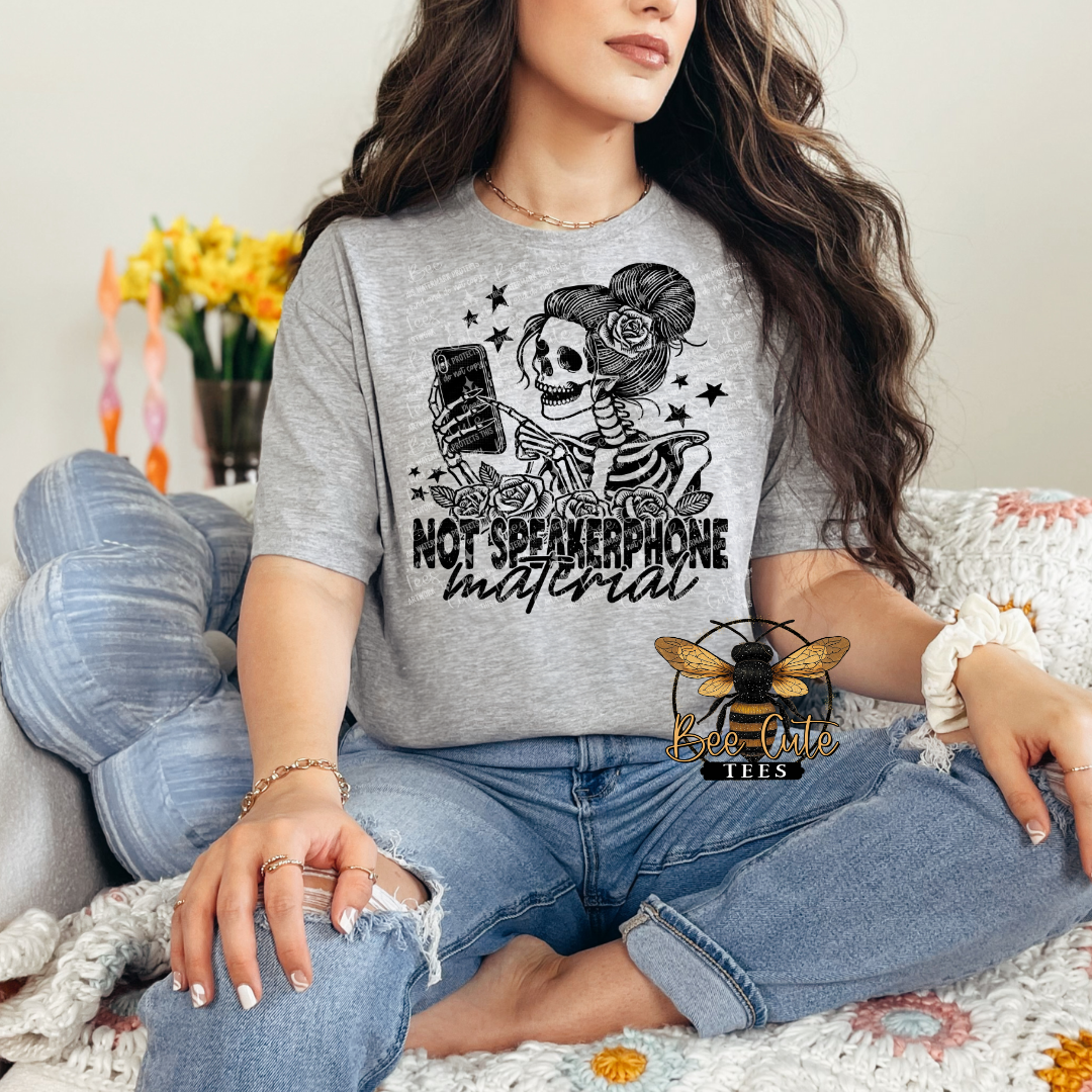 Person wearing a gray t-shirt with a skeleton design and text, sitting on a couch.