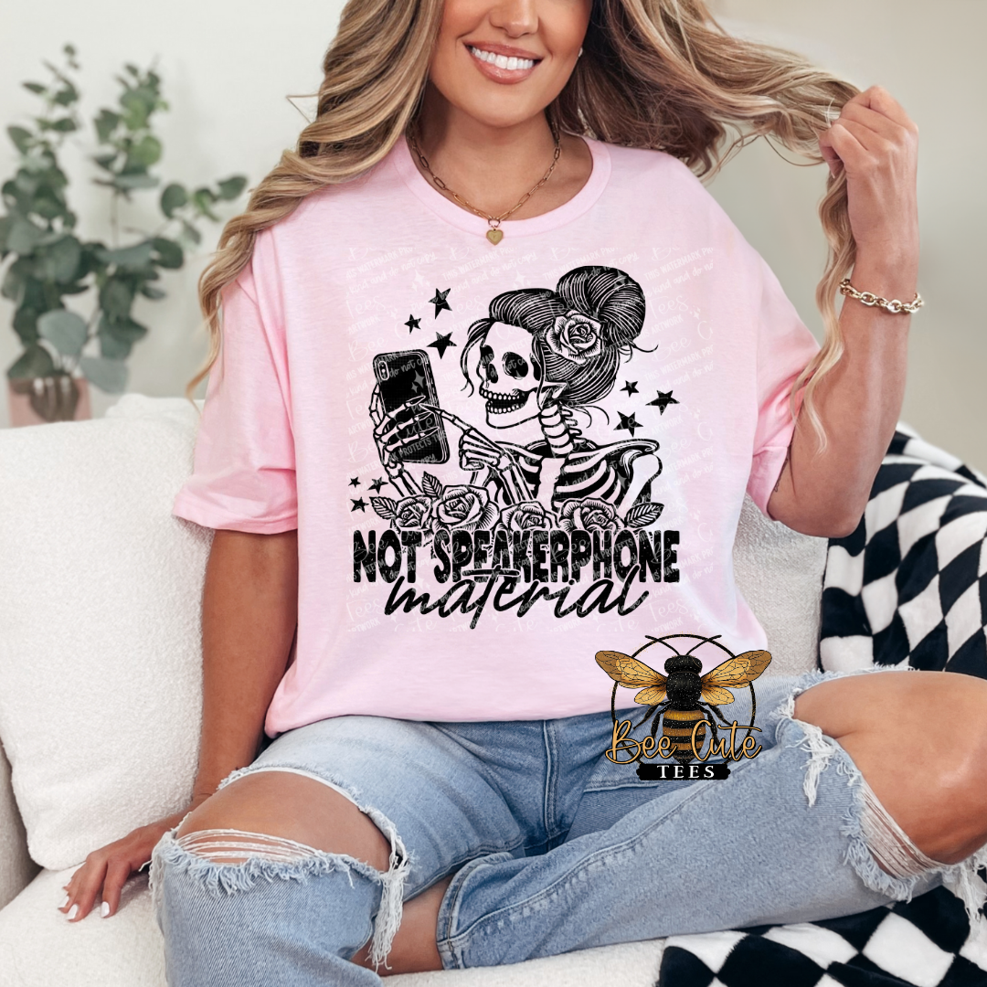 Person wearing a pink t-shirt with a skeleton design and text, sitting on a couch.