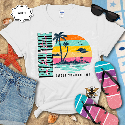 White t-shirt with a colorful beach-themed design, sunglasses, flip-flops, and denim shorts on a sandy background.