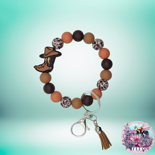 Beaded keychain with cowboy boot charm on a gradient background