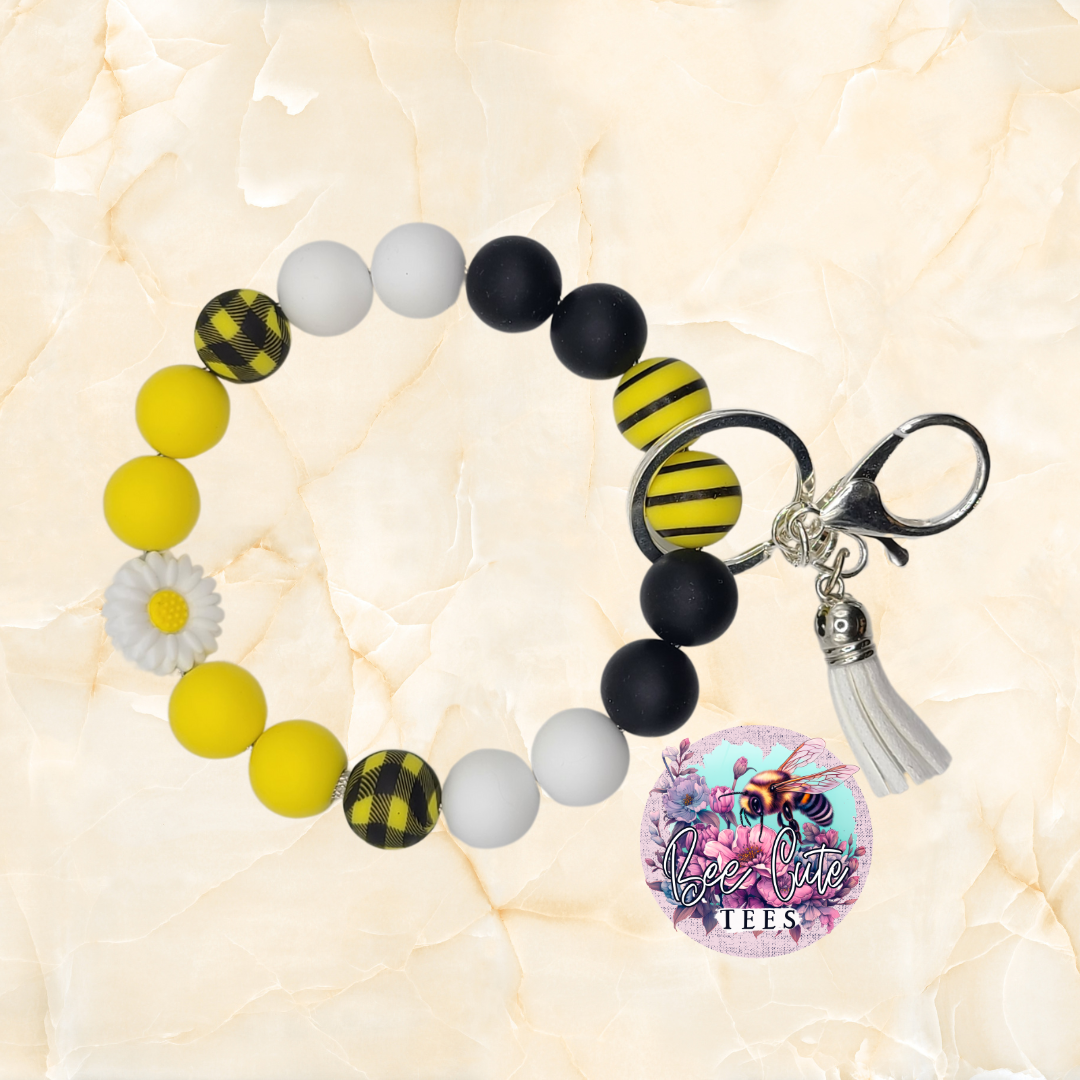 Beaded bracelet with bee-themed keychain and charm on a light background