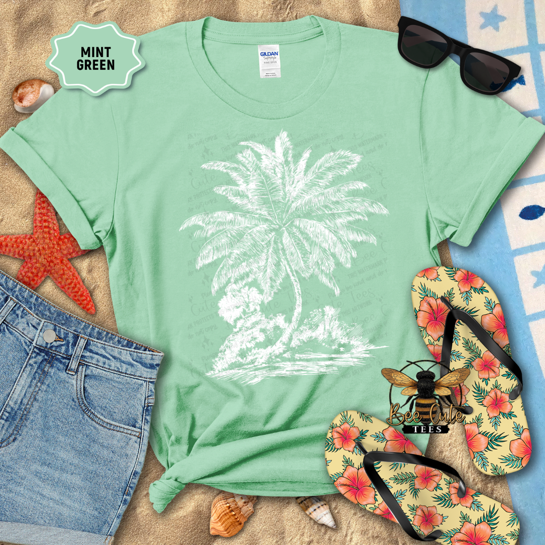 Mint green t-shirt with palm tree design, sunglasses, flip-flops, and beach items on a sandy background.