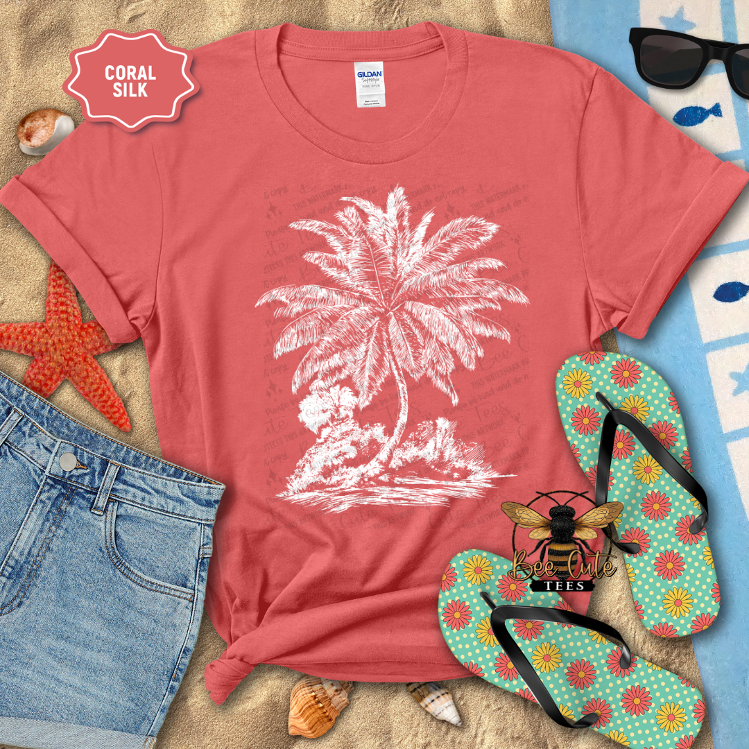 Red t-shirt with white palm tree design on a sandy background with beach accessories.