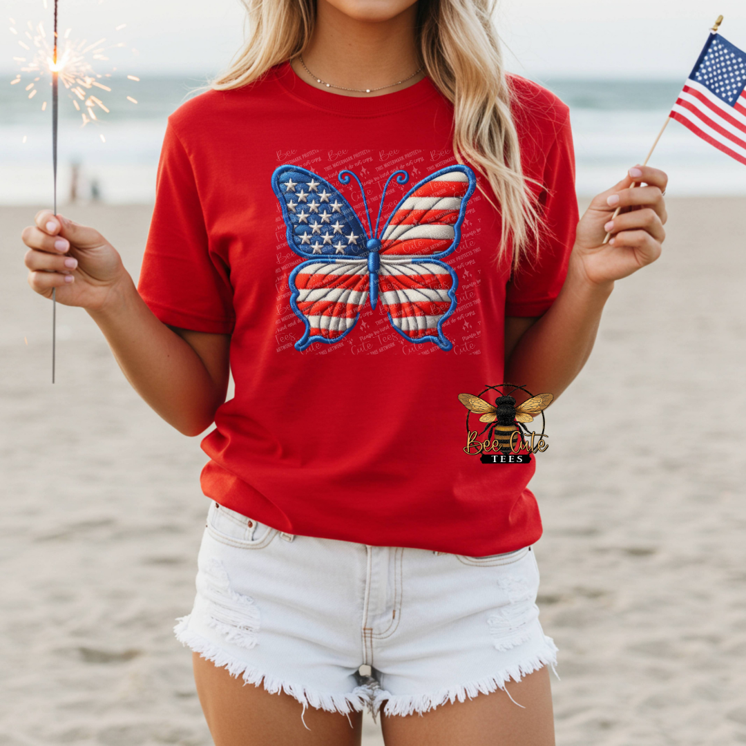 Person wearing a red t-shirt with a butterfly design on a beach