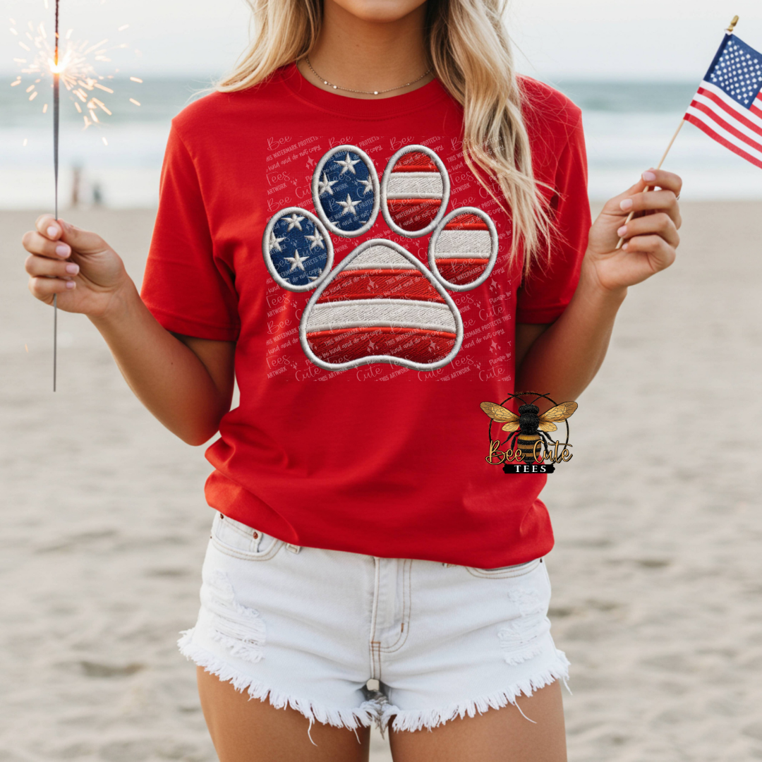 Person wearing a red t-shirt with a paw print design on a beach